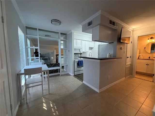 a kitchen with a refrigerator and table chairs in it