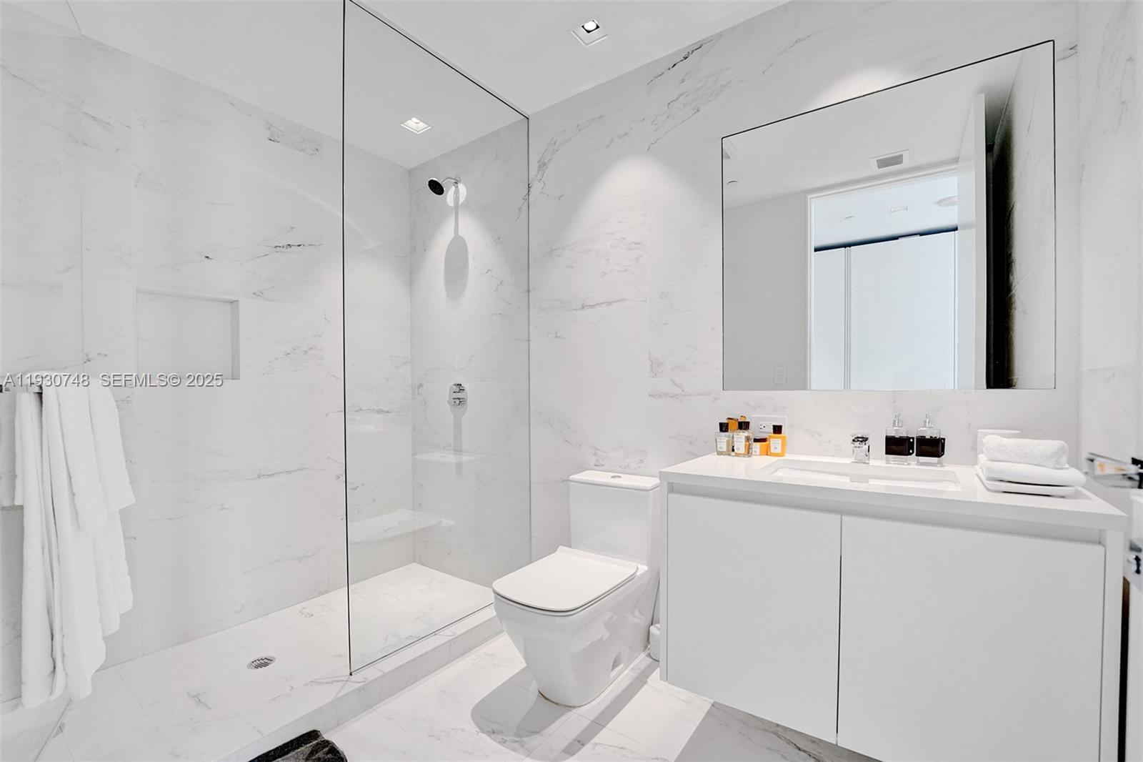 1000 Biscayne Boulevard, Unit 3902 Miami, FL 33132 - Photo 18 of 51 a bathroom with a toilet a sink a mirror and shower