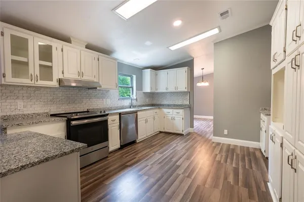 a kitchen with granite countertop wooden floors stainless steel appliances and sink