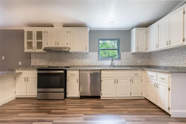 a kitchen with granite countertop cabinets stainless steel appliances a sink and a window