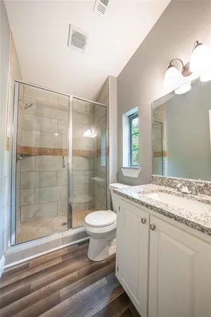 a bathroom with a granite countertop sink toilet a mirror and shower