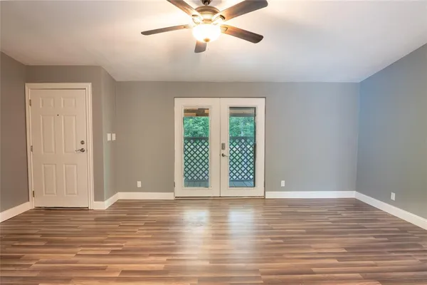 a view of an empty room with wooden floor and a window