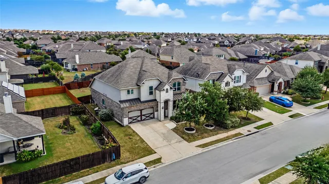 an aerial view of residential houses with outdoor space and parking