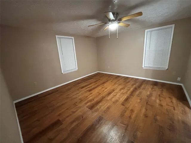 a view of an empty room with window and chandelier fan