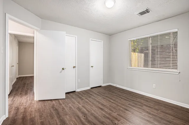 a view of an empty room with wooden floor and a window