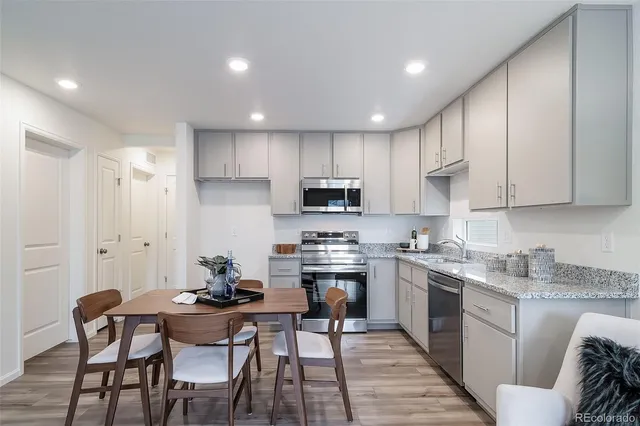 a kitchen with stainless steel appliances granite countertop a table chairs sink refrigerator and cabinets