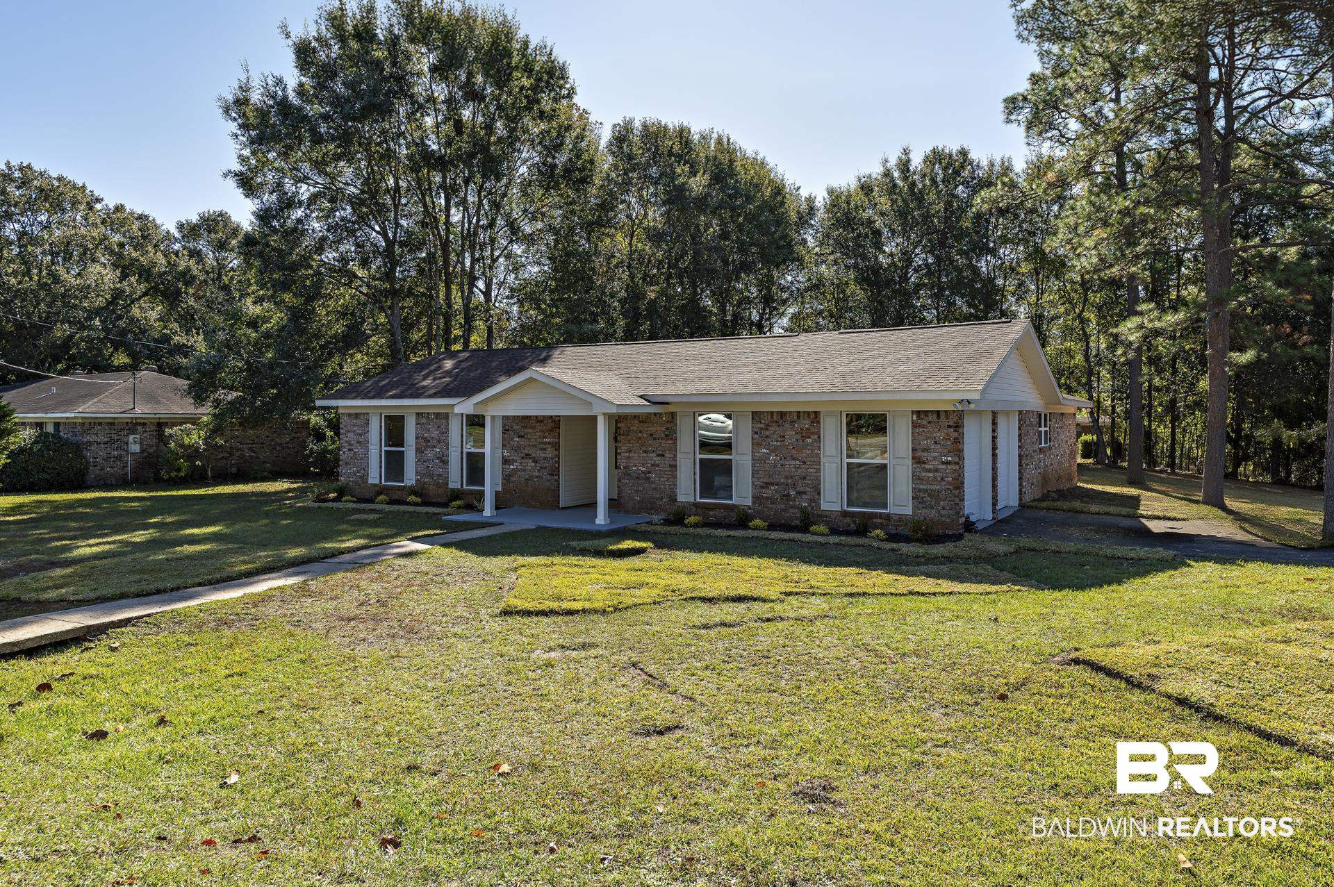 6001 Camp Halls Mill Road Mobile, AL 36619 - Photo 1 of 52 Ranch-style home with a front lawn, brick siding, roof with shingles, and view of wooded area
