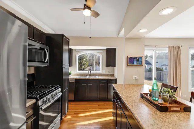 a kitchen with stainless steel appliances kitchen island granite countertop a stove refrigerator and cabinets