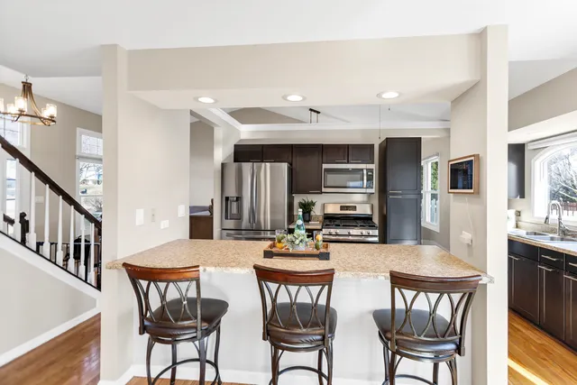 a kitchen with stainless steel appliances a dining table chairs and stove