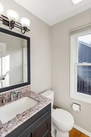 a bathroom with a granite countertop sink mirror vanity and toilet