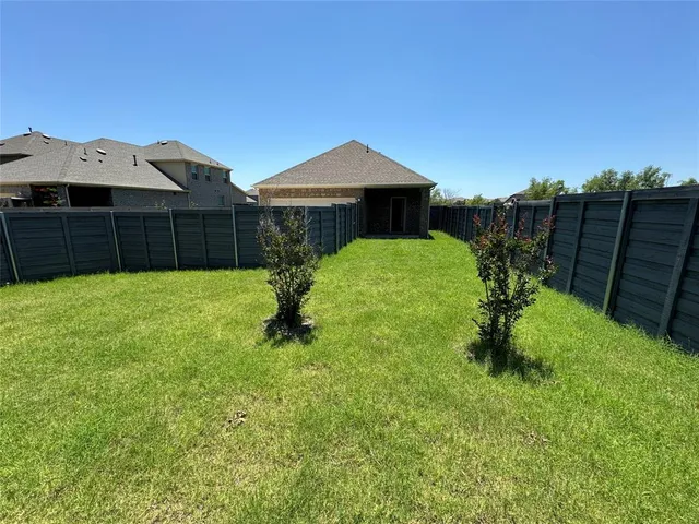a backyard of a house with plants and wooden fence