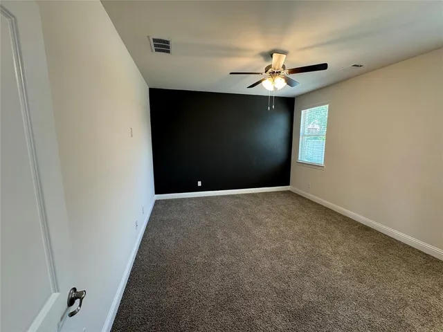 an empty room with a ceiling fan and a window
