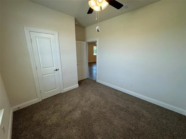 an empty room with a ceiling fan and bathroom view