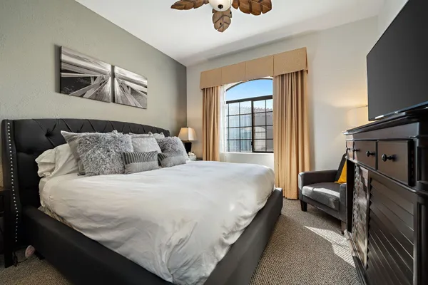 a bedroom with a bed a couch and a flat tv screen
