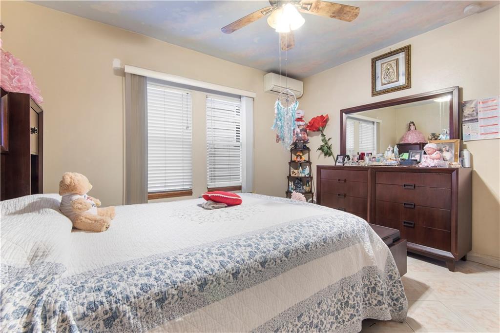 8745 17th Avenue Brooklyn, NY 11214 - Photo 11 of 31 a bedroom with a large bed and a chandelier