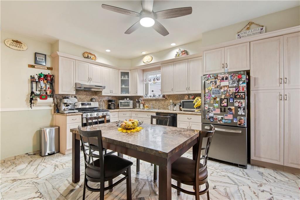 8745 17th Avenue Brooklyn, NY 11214 - Photo 6 of 31 a kitchen with stainless steel appliances a dining table chairs refrigerator and sink