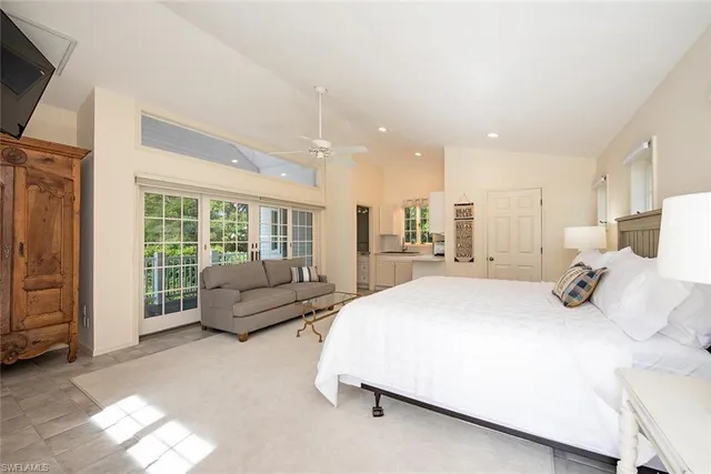 a spacious bedroom with a bed a couch and large window