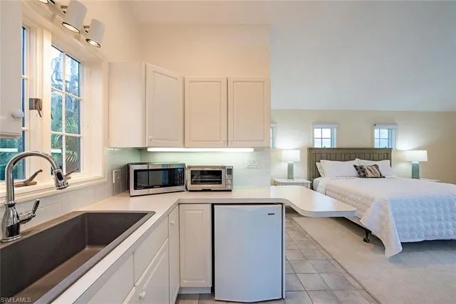 a kitchen with a sink dishwasher a stove top oven a refrigerator with white cabinets and wooden floor