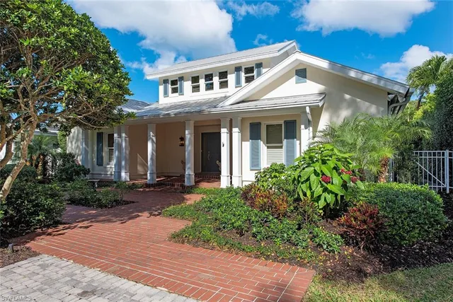 a view of a white house next to a yard with potted plants