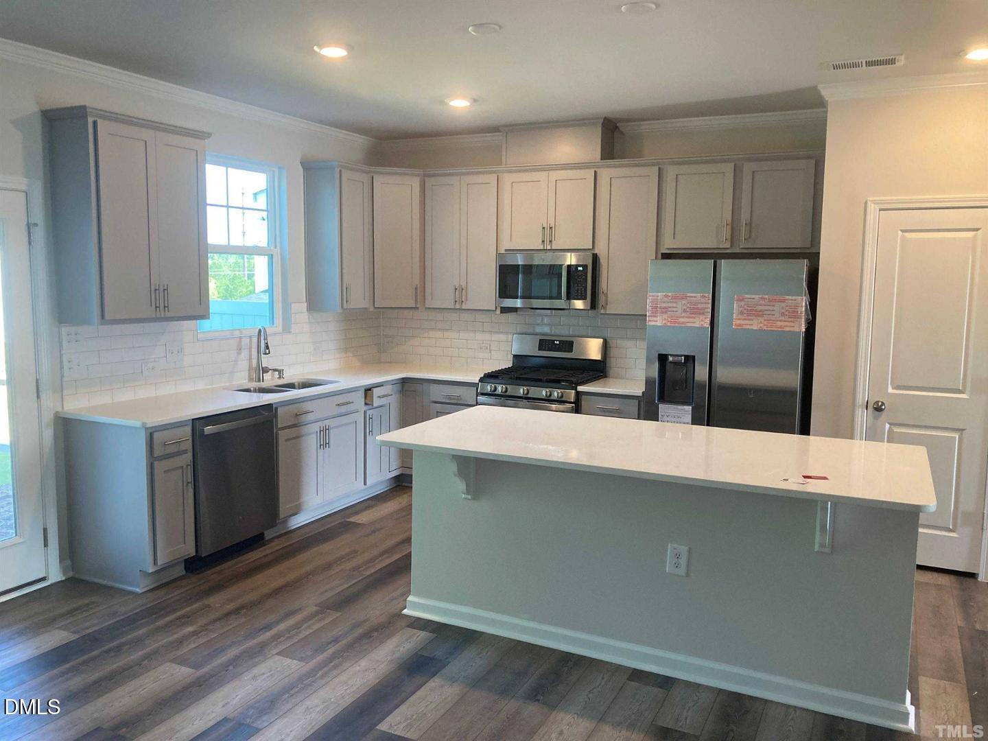 1823 Caen Street Raleigh, NC 27610 - Photo 13 of 13 a kitchen with kitchen island white cabinets a sink a stove a refrigerator and microwave