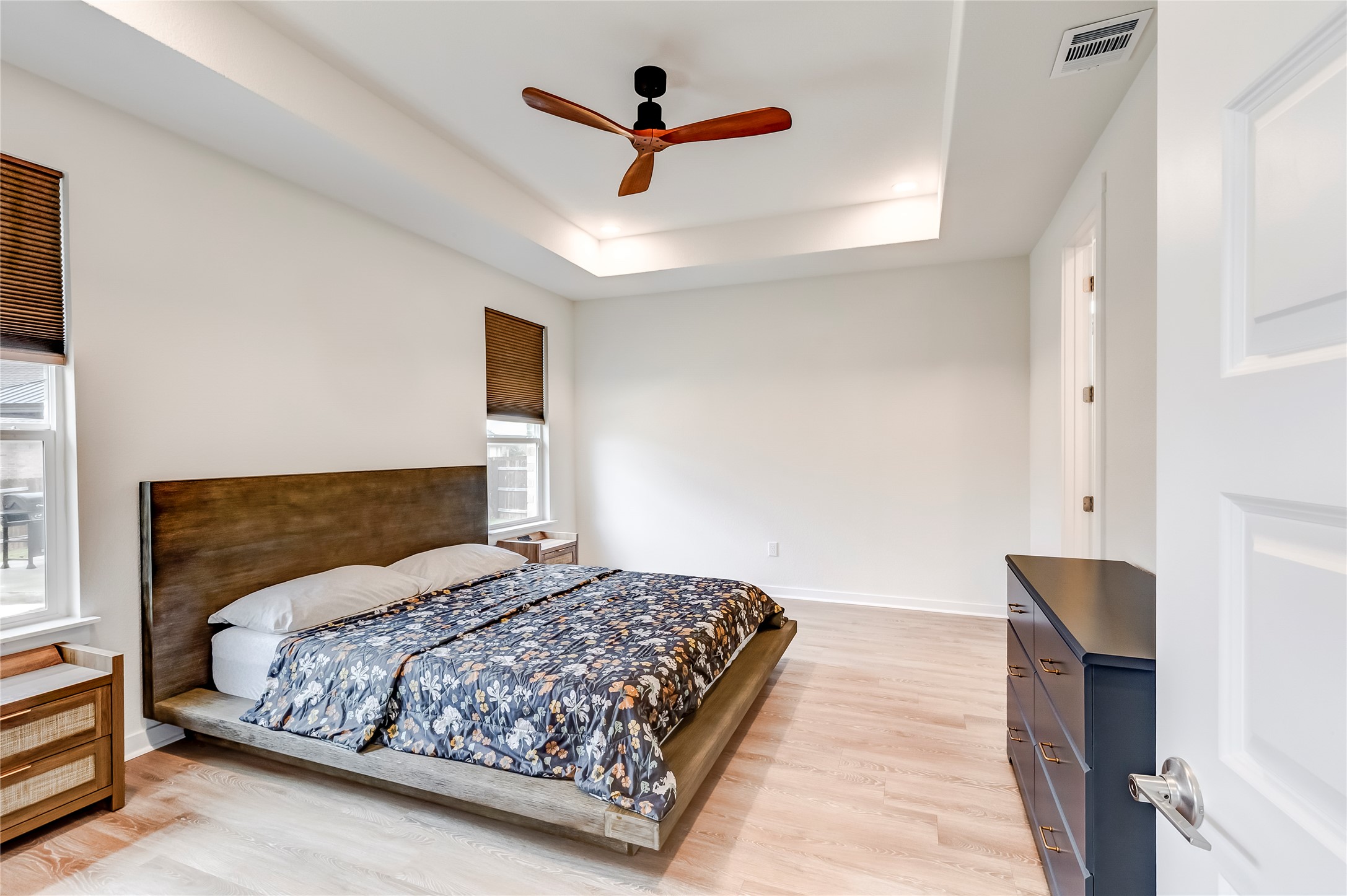 917 Balsora Cove Georgetown, TX 78628 - Photo 18 of 39 Bedroom with light wood-style floors, a ceiling fan, and a tray ceiling