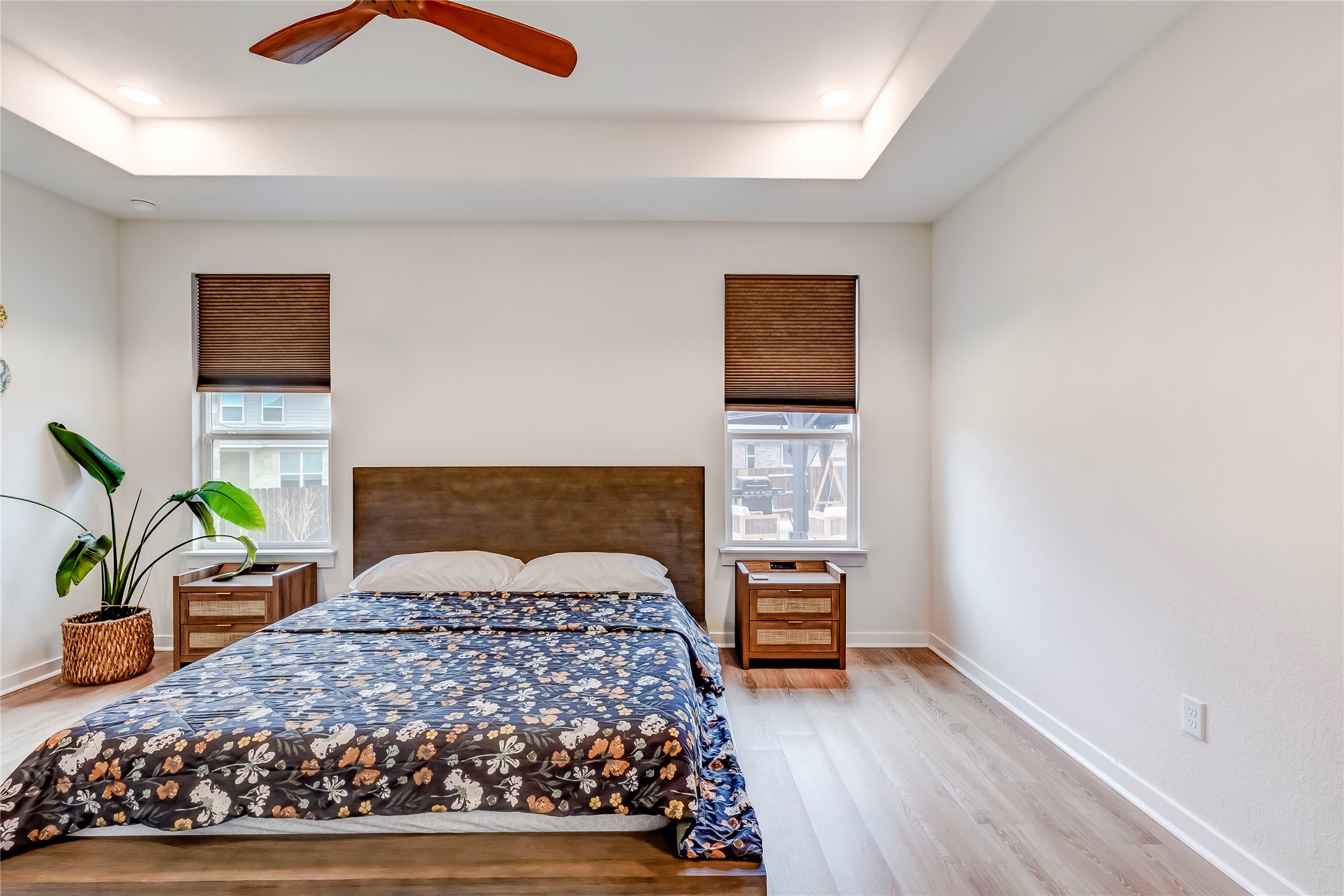 917 Balsora Cove Georgetown, TX 78628 - Photo 21 of 39 Bedroom featuring a tray ceiling, multiple windows, light wood finished floors, ceiling fan, and recessed lighting