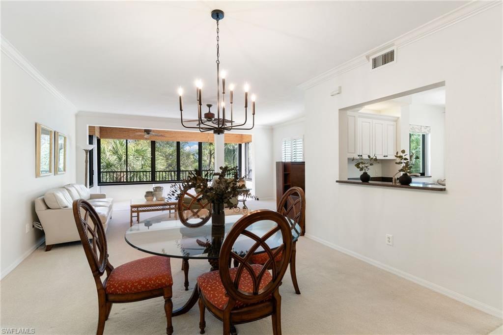 6500 Valen Way, Unit A203 Naples, FL 34108 - Photo 11 of 28 a view of a dining room with furniture wooden floor and chandelier