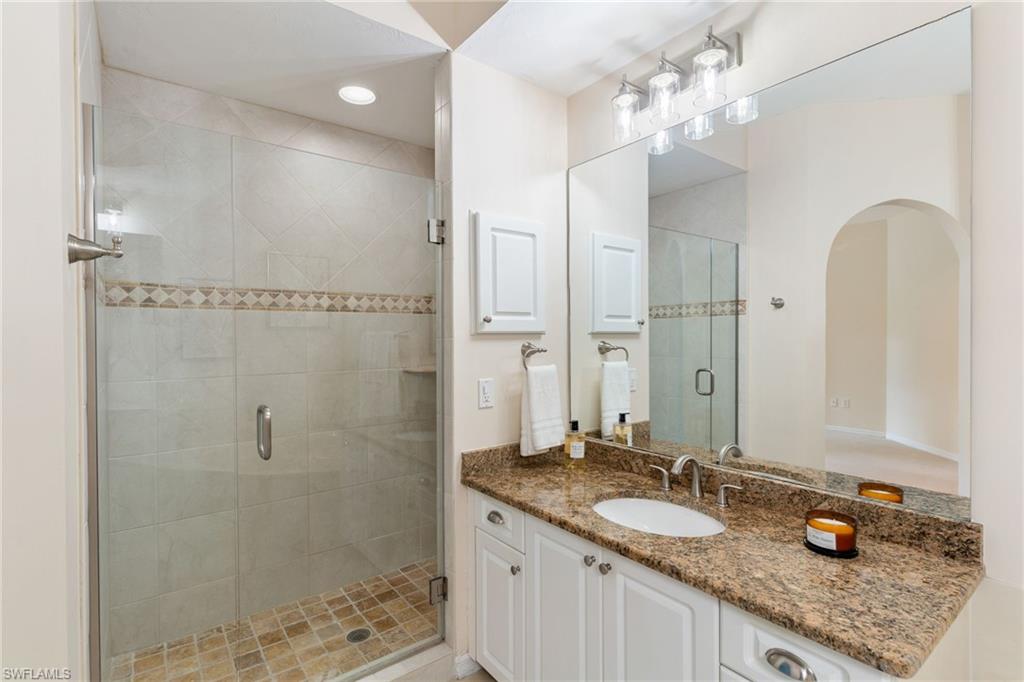 6500 Valen Way, Unit A203 Naples, FL 34108 - Photo 21 of 28 a bathroom with a granite countertop sink a mirror and shower