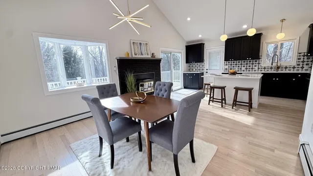 a kitchen with stainless steel appliances kitchen island granite countertop a stove a refrigerator a kitchen island a dining table and chairs with wooden floor