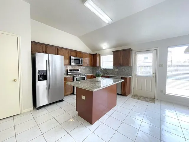 a kitchen with stainless steel appliances granite countertop a refrigerator and a stove top oven