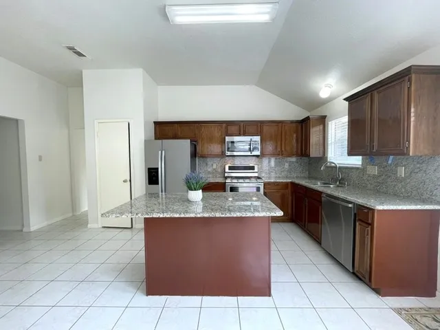 a large kitchen with granite countertop a stove a sink dishwasher and a refrigerator