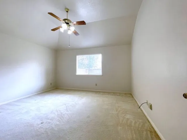 an empty room with a chandelier fan and windows