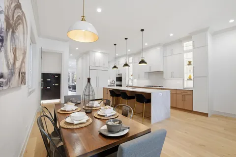 a kitchen with stainless steel appliances kitchen island granite countertop a kitchen island a stove a dining table and chairs with wooden floor