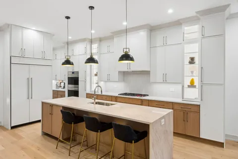 a kitchen with stainless steel appliances granite countertop a table chairs wooden floors and white cabinets