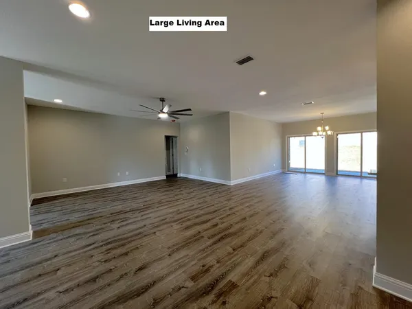 an empty room with wooden floor cabinet and windows