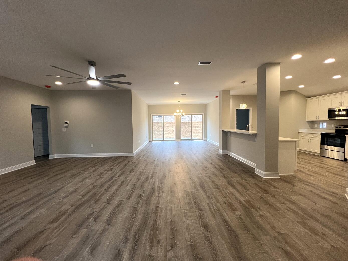445 Scooter Cove Crestview, FL 32539 - Photo 9 of 22 a view of an empty room and kitchen with wooden floor