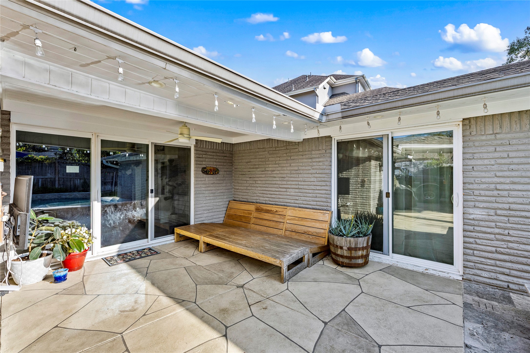 8422 Academy Street Houston, TX 77025 - Photo 33 of 47 Inviting patio space featuring with plenty of room for patio furniture, string lighting, and easy access to the pool through multiple sliding doors. Perfect for outdoor lounging, morning coffee, or relaxing after a swim.