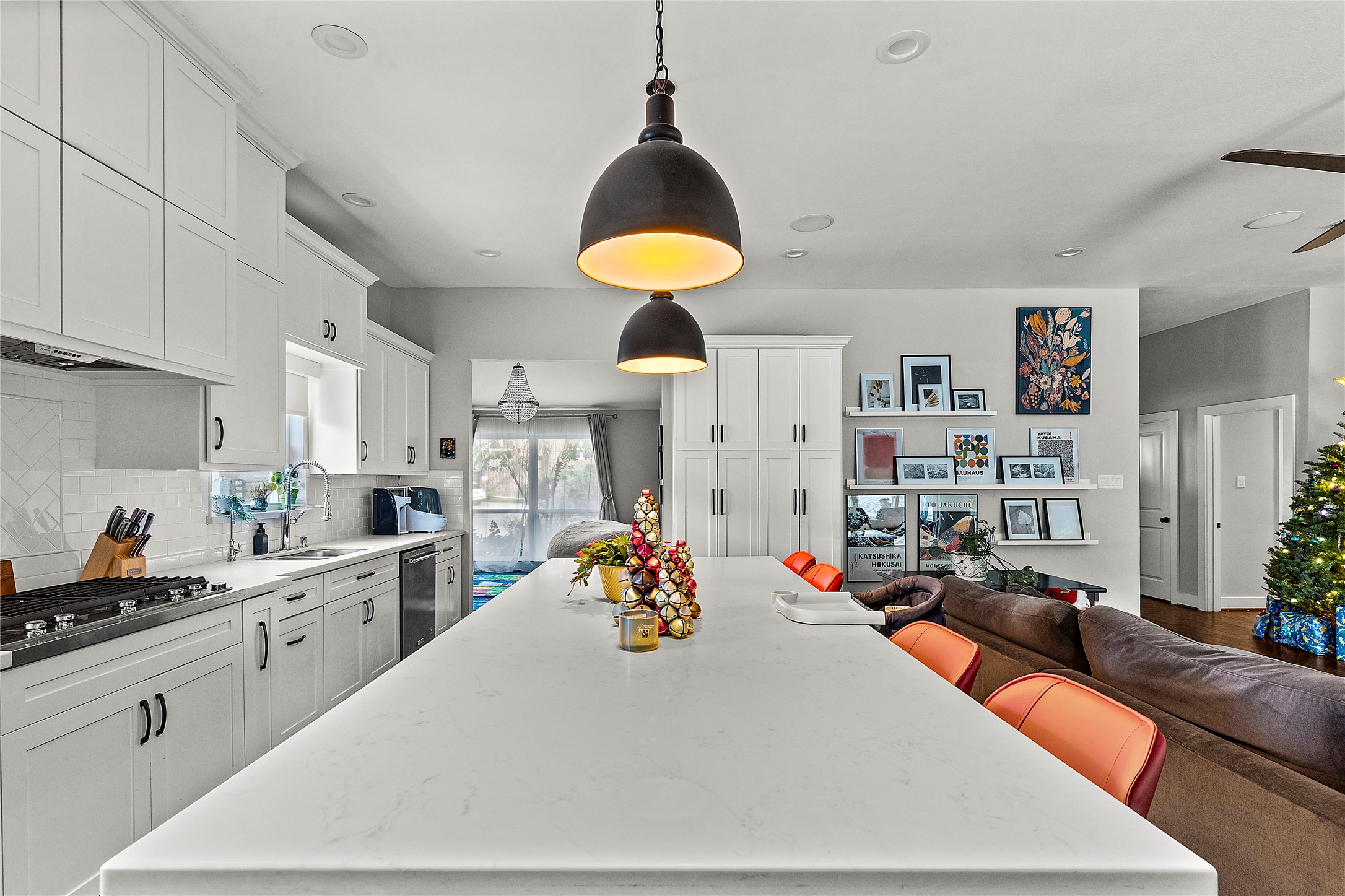 8422 Academy Street Houston, TX 77025 - Photo 7 of 47 Spacious open-concept layout featuring an oversized quartz island with pendant lighting, perfect for cooking, gathering, and entertaining. The kitchen seamlessly flows into the bright living area, complete with custom built-ins, abundant storage, and views of the backyard through large windows.