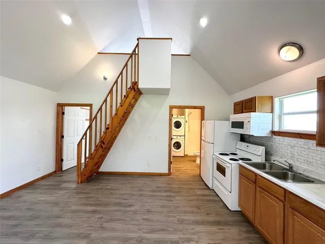 a kitchen with granite countertop a stove a sink and a refrigerator
