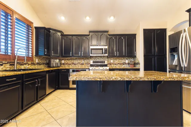a kitchen with kitchen island granite countertop a sink stove and refrigerator