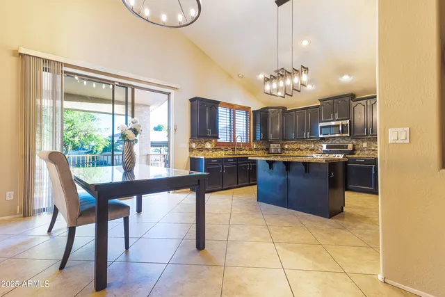 a kitchen with stainless steel appliances granite countertop a stove a refrigerator a sink dishwasher with a dining table and chairs