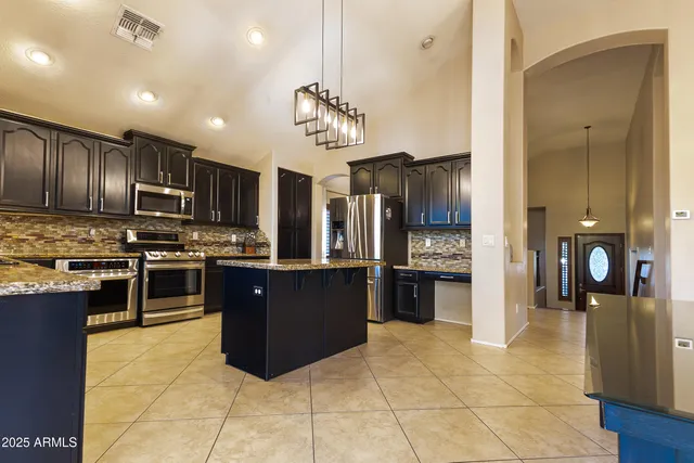 a kitchen with stainless steel appliances granite countertop a refrigerator and a stove top oven
