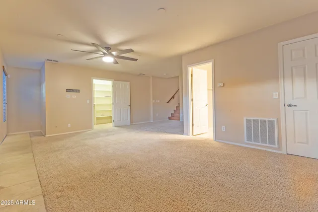 an empty room with chandelier fan and windows