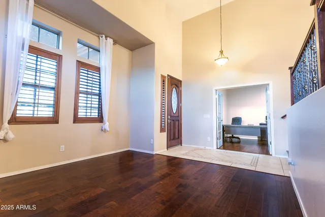 a view of an empty room with window and hardwood floor