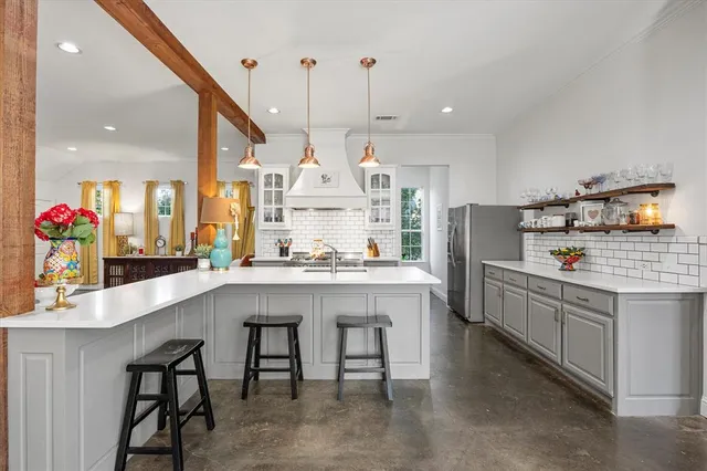 a kitchen with kitchen island granite countertop a table chairs sink and cabinets