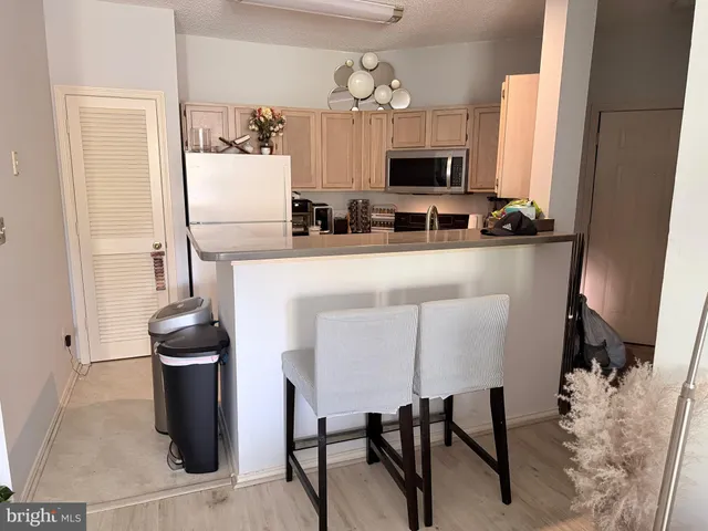 a kitchen with stainless steel appliances kitchen island a table chairs in it and wooden floors