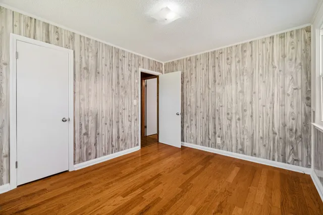 an empty room with wooden floor and mirror
