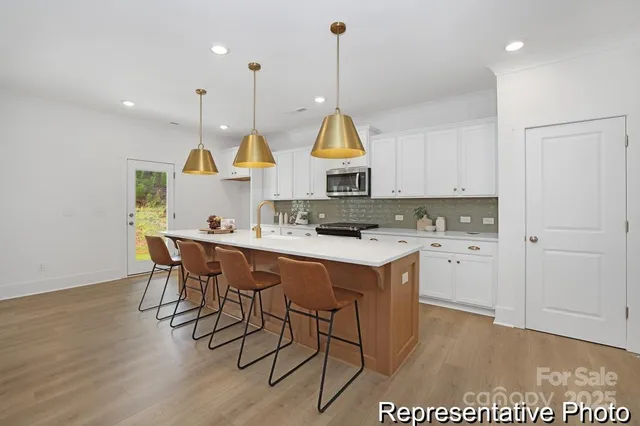 a kitchen with stainless steel appliances granite countertop a sink a stove a refrigerator and wooden floor