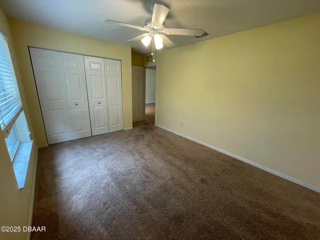 a view of an empty room and chandelier fan