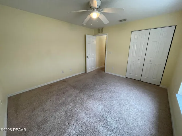 an empty room with a ceiling fan and a window